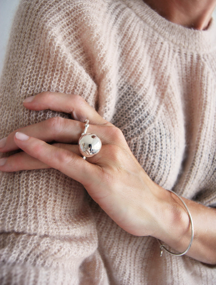 tjej som bär en silverring med stor kula och en smalare ring med flera kulor.
