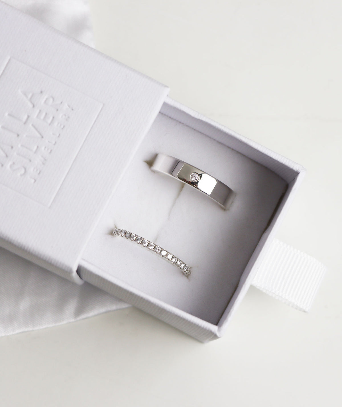 Ring set med vigsel eller förlovningsringar till henne och honom, placerade i en vit ask från Mila Silver