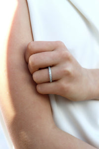 Tjej som bär en diamantring, alliansring med band av många så diamanter. 