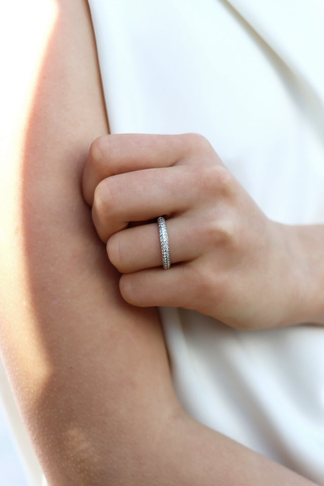 Tjej som bär en diamantring, alliansring med band av många så diamanter. 