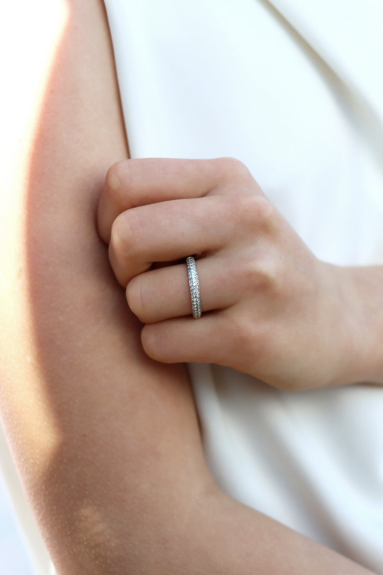 Tjej som bär en diamantring, alliansring med band av många så diamanter. 