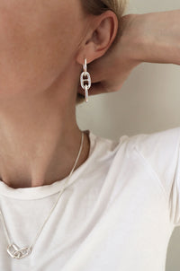 Tjej som bär halsband och örhängen med ankarlänkar i silver. 