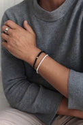 Man som bär ett silverarmband med vriden kedja - Rope Chain / Cordell kedja i silver. Kombinerat med svart stenarmband. 
