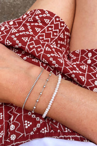 pärlarmband med små pärlor kombinerat med två tunna silverarmband.