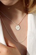 Tjej som bär ett halsband med bokstavsberlock i silver med graverat M och liten diamant