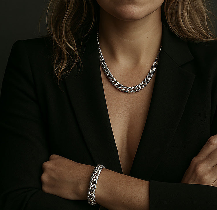 Kvinna som bär ett brett kedjehalsband med matchande armband i silver. Kedjemodell: Pansarkedja. 