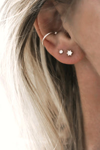 Tjej som bär flera små diamantörhängen i örat kombinerat med en ear cuff