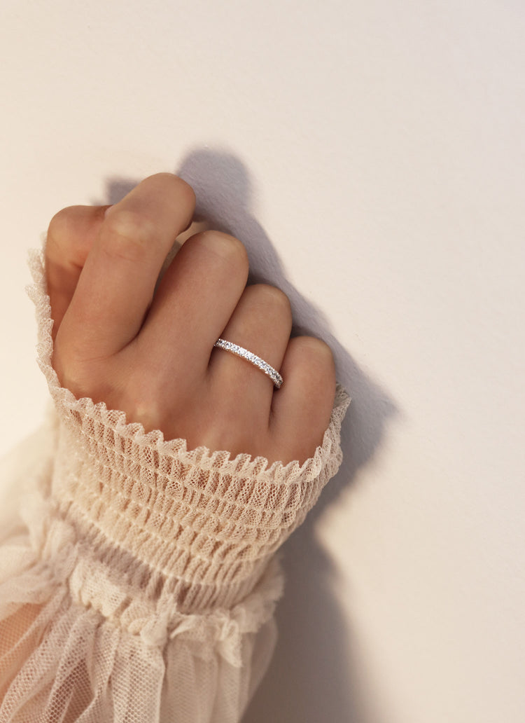 diamantring med ett band av vita diamanter som bärs på ringfingret. 