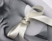 En diamantring med oval stor diamant placerad på en sidenrosett. 