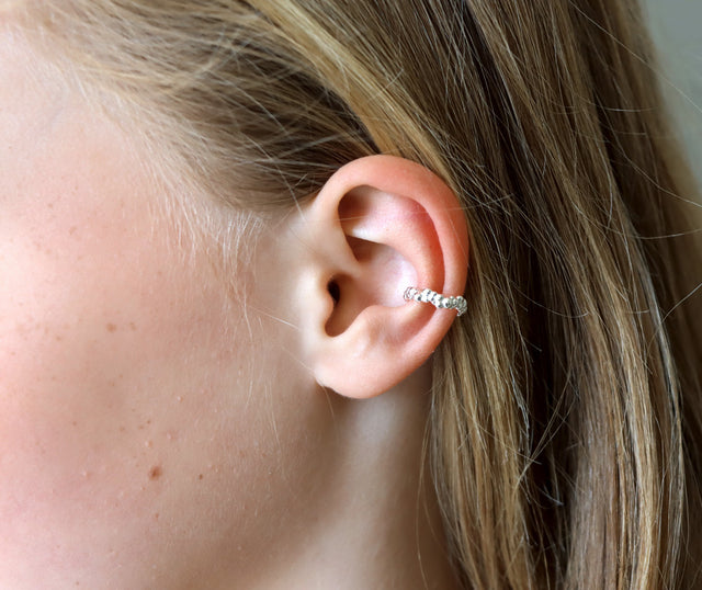 Tjej som bär en ear cuff mitt på örat. Ear cuff i äkta silver med små silverkulor.