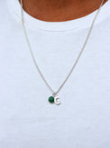 Man som bär ett halsband i silver med pansarkedja, grön jade-sten och bokstavsberlock G