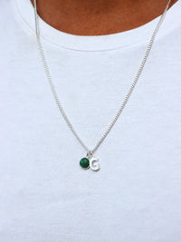 Man som bär ett halsband i silver med pansarkedja, grön jade-sten och bokstavsberlock G
