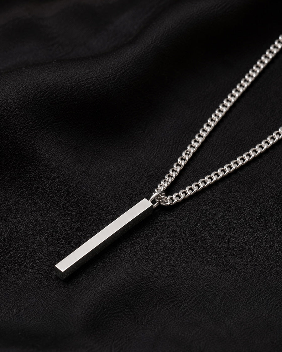 Silverstav i kedja - halsband till herr, placerat på ett svart tyg. 