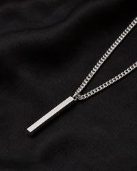 Silverstav i kedja - halsband till herr, placerat på ett svart tyg. 