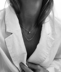 Tjej som bär två silverhalsband i olika längder. 