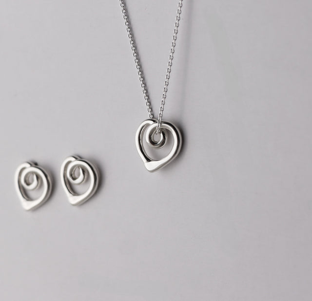 Silverhalsband med ett hängsmycke utformat som ett hjärta med organiska former, sett från sidan. 