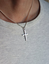 Man som bär ett halsband med ett silverkors