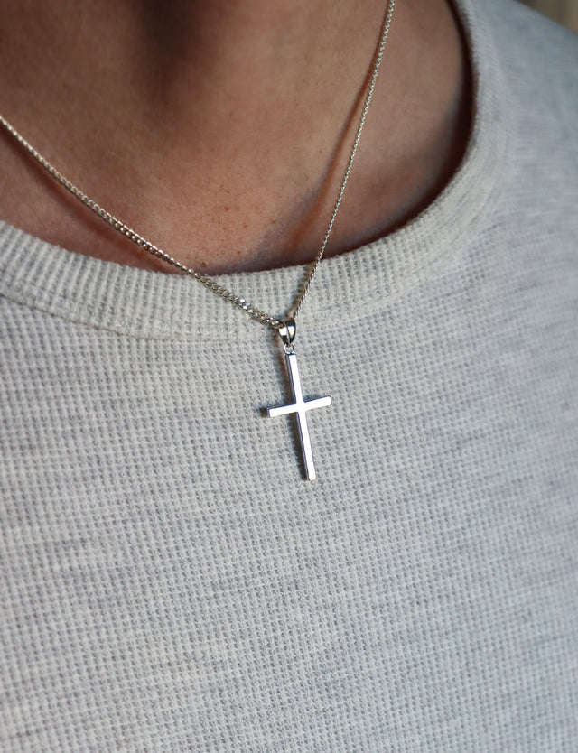 Man som bär ett halsband med ett silverkors