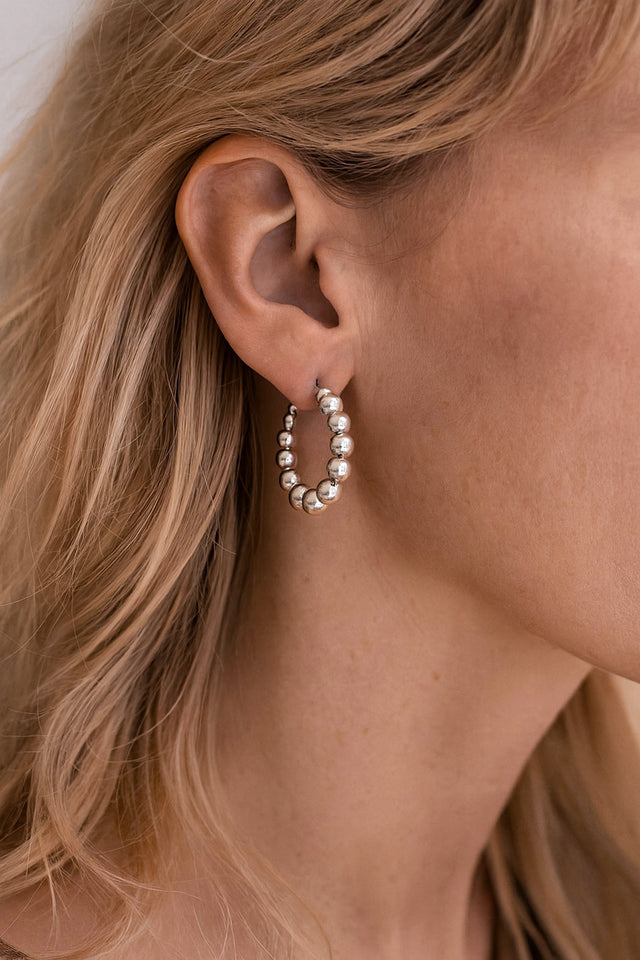 Tjej som bär silver hoops med kulor. 