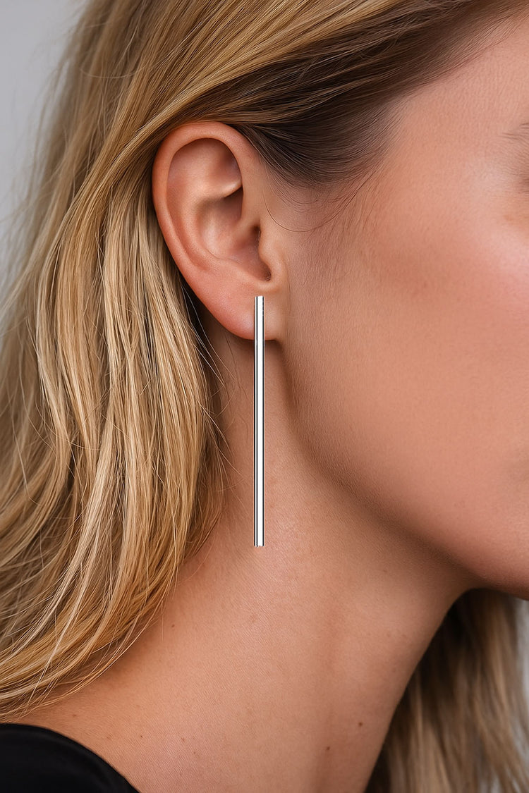 Tjej som bär långa hängande stavar i öronen