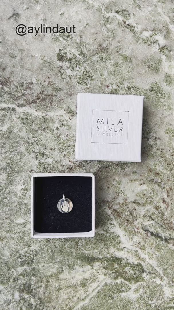 video som visar en mamma som packar upp ett halsband från Mila Silver med  en berlock i silver som har dotterns handavtryck graverat. 