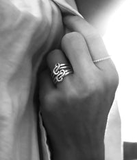 Två silverringar med evighet knutar som bärs på samma finger i en kombination.