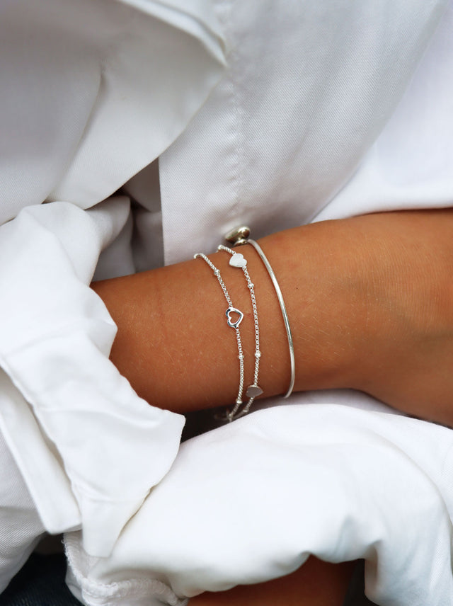 Tjej som bär ett armband i silver med flera små silverhjärtan på kedja. 