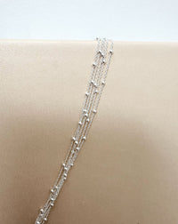 Närbild på tunna silverkedjor med små kulor. 