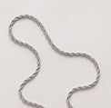 Silverkedja med vridna trådar som ett rep, ligger på ett bord. Modell Rope chain. 