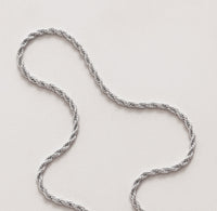 Silverkedja med vridna trådar som ett rep, ligger på ett bord. Modell Rope chain. 