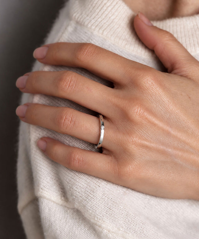 Tjej som bär en smal silverring med en liten diamant som sitter i ringen.
