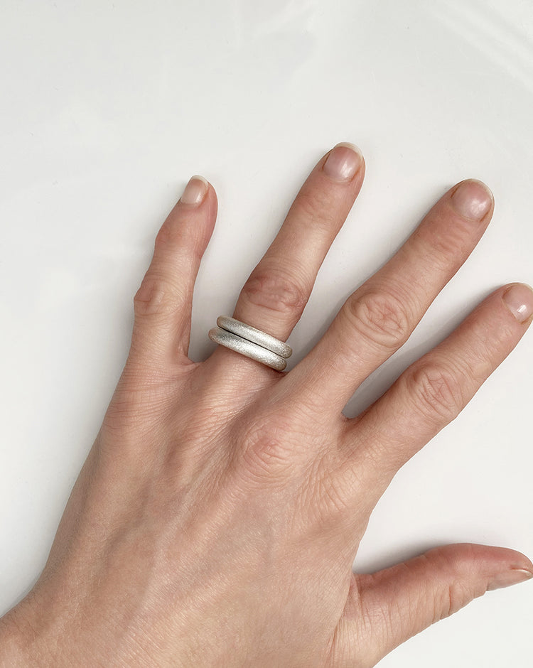 Två tjocka silverringar med matta ytor i en ring stack. 