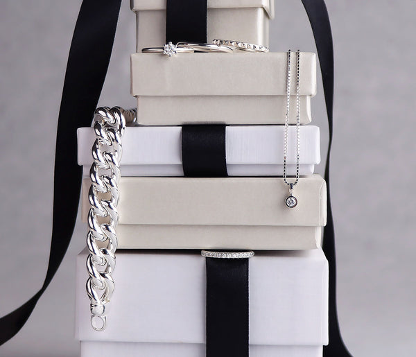 En stapel med present-askar där silversmycken är placerade mellan askarna. 